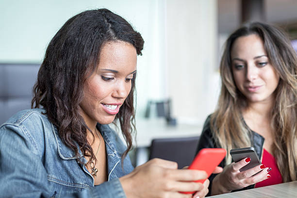 istock Two young women friends at bar while using mobile phones 495732014