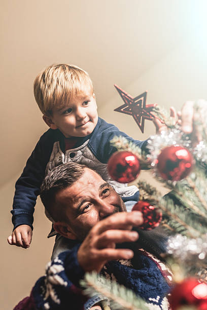 Father and son put tree topper on the Christmas tree