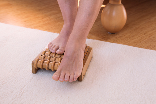 feet on wooden massage roller in bedroom