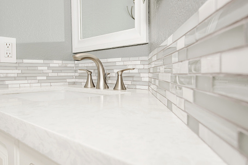 The detail of a newly remodeled bathroom faucet and counter.