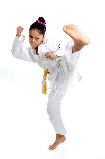 cute latin little girl in karate kimono training kick attack sweet latin little girl stretching leg in martial arts practice training kick and attack in plastic action like karate kid  isolated on white background martial arts photos stock pictures, royalty-free photos & images
