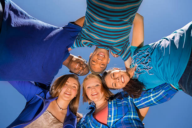 istock Teenagers: Group of friends huddle together. Blue sky. 495745501