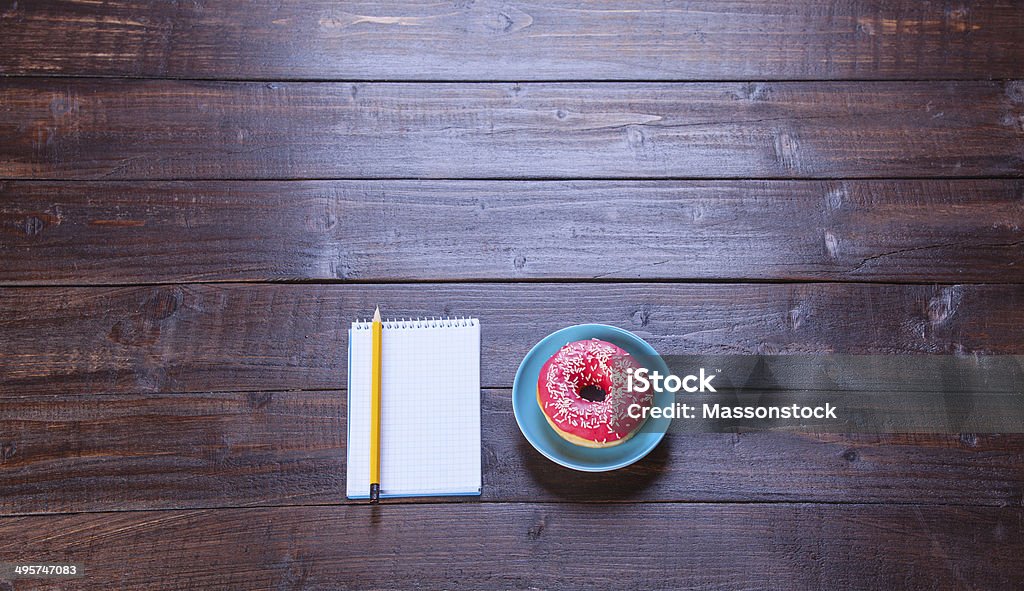 Notebook, donut and pencil on wooden table. Blank Stock Photo