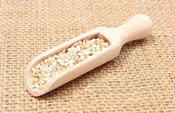 istock Barley groats with wooden spoon lying on jute canvas 495748257