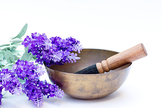 Studio shot of a Tibetan bowl decorated with purple fabric flowers isolated on white background.