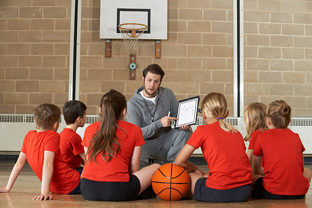 Coach Giving Team Talk To Elementary School Basketball Team Coach Giving Team Talk To Elementary School Basketball Team high school student child little boys junior high stock pictures, royalty-free photos & images