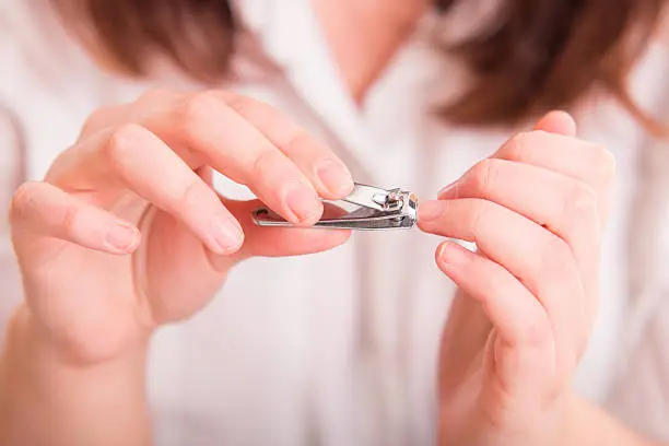 Woman cutting nails using nail clipper - close up