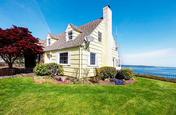 istock Yellow small home with water view and red maple. 495756531