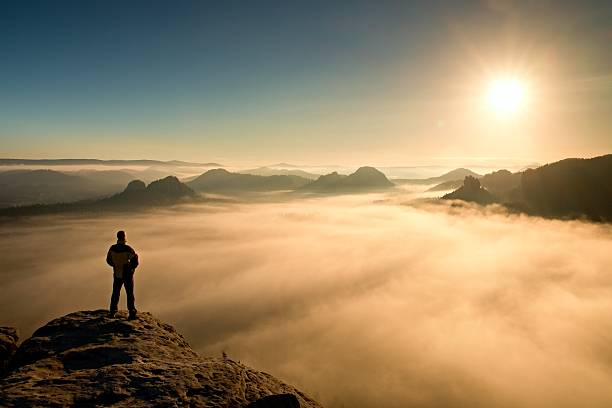Man stands on peak and watching to Sun. Beautiful miracle stock photo