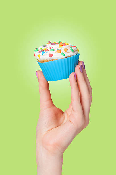 istock Hand holding cupcake on green background 495757487