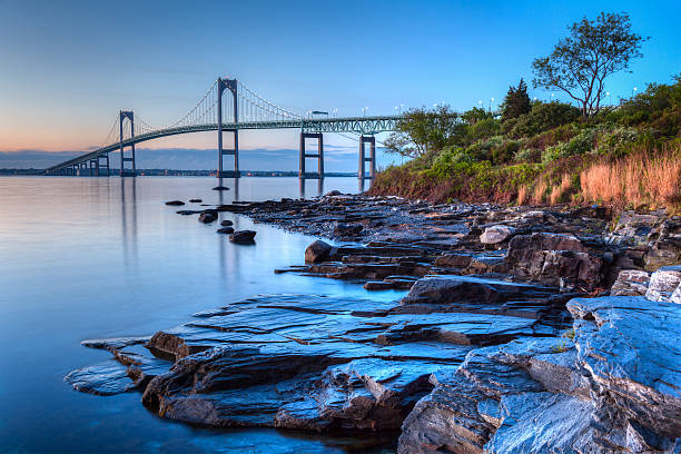 Newport Bridge Sunrise This is a long exposure HDR of the illuminated Newport bridge from Taylor's Point near Jamestown, Rhode Island, USA. It was taken at sunrise with a rocky seascape in the foreground. rhode island photos stock pictures, royalty-free photos & images