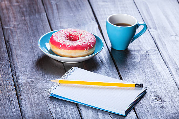 istock Cup of coffee with notebook and donut. 495757619