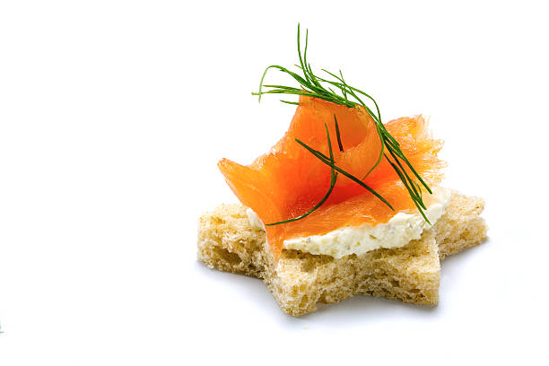 canape in star shape with smoked salmon on horseradish cream and dill garnish for a Christmas buffet, isolated on a white background