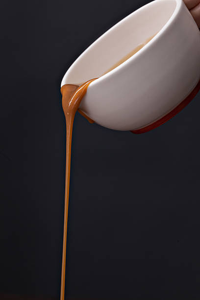 Pouring Gravy A close up vertical photograph of a hand holding a white gravy boat and pouring a long stream of savory beef or turkey gravy. gravy stock pictures, royalty-free photos & images