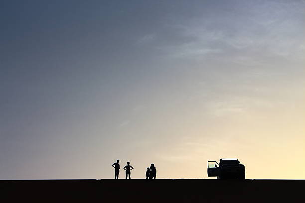 Pack of adventurers salute from the top of a dune A pack of adventurers salute from the top of a grand sand dune while enjoying a beautiful summer sunset in Dakhla Oasis, Egypt. egypt horizon over land sun shadow stock pictures, royalty-free photos & images