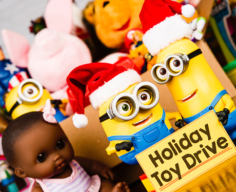 Peyton, Colorado, USA - November 3, 2015: A horizontal studio shot of two Minion toys wearing Santa hats and holding a Holiday Toy Drive banner. Behind the toys is a box filled with a variety of American brand toys. This image shows Minion Bob and Minion Kevin. The characters are from the Universal Studios 2015 animated movie called Minions, which is a comedy for family audiences. The toys are manufactured for Thinkway Toys. THIS IMAGE IS FOR EDITORIAL USE ONLY.
