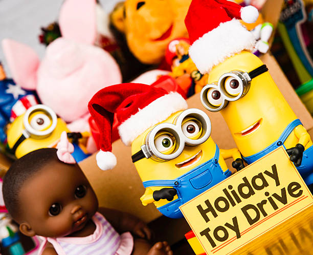 Minion Bob and Kevin promoting a toy drive Peyton, Colorado, USA - November 3, 2015: A horizontal studio shot of two Minion toys wearing Santa hats and holding a Holiday Toy Drive banner. Behind the toys is a box filled with a variety of American brand toys. This image shows Minion Bob and Minion Kevin. The characters are from the Universal Studios 2015 animated movie called Minions, which is a comedy for family audiences. The toys are manufactured for Thinkway Toys. THIS IMAGE IS FOR EDITORIAL USE ONLY. winnie the pooh photos stock pictures, royalty-free photos & images