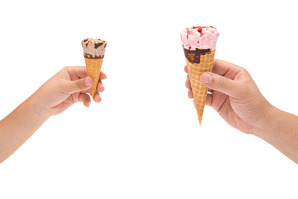 istock boy holding small ice cream cone and man holding big 495763556