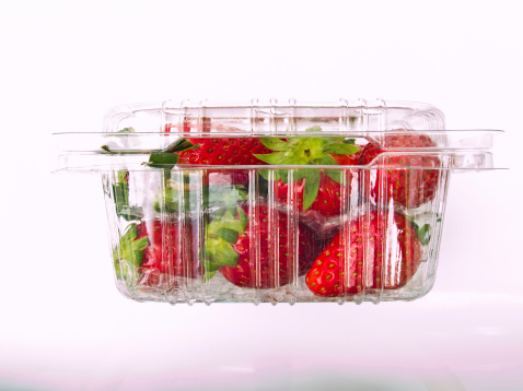Fresh Strawberry piled in clear plastic box as background