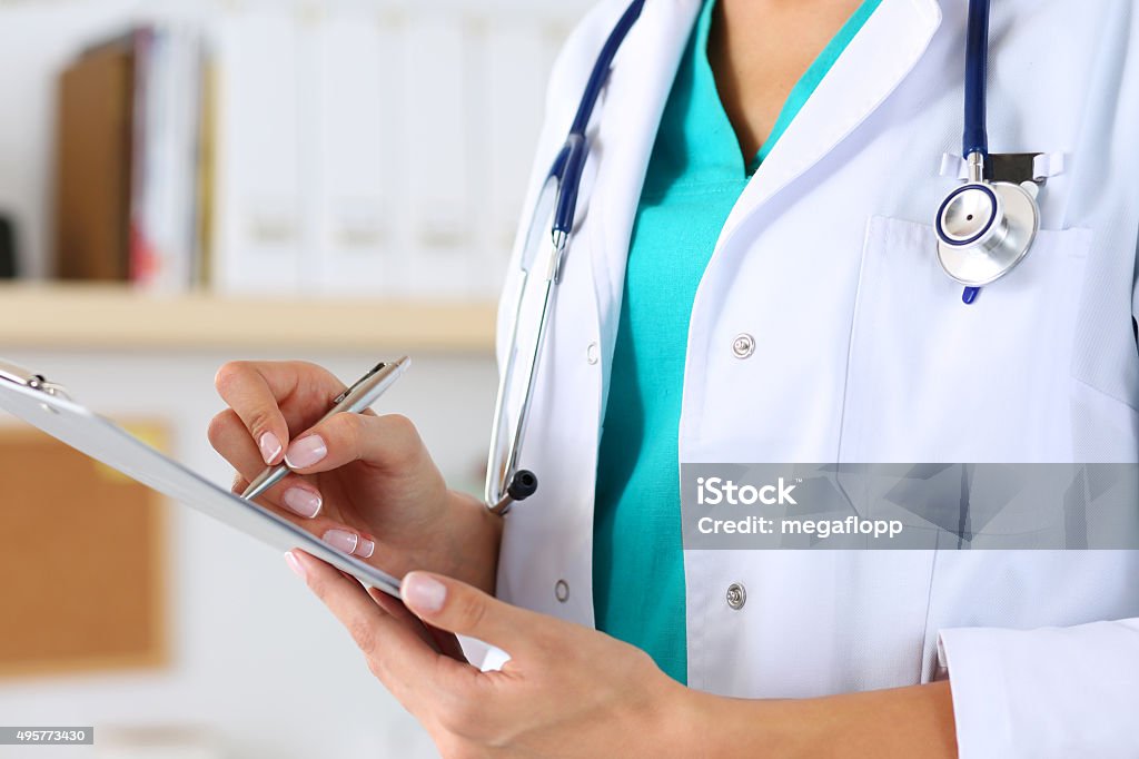 Female medicine doctor hand holding silver pen Female medicine doctor hand holding silver pen writing something on clipboard closeup. Medical care, insurance, prescription, paper work or career concept. Physician ready to examine patient and help Doctor Stock Photo