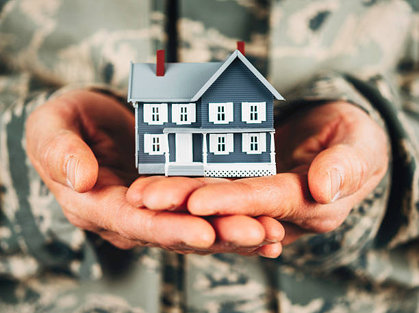 Military service member holding little house. Relocation.