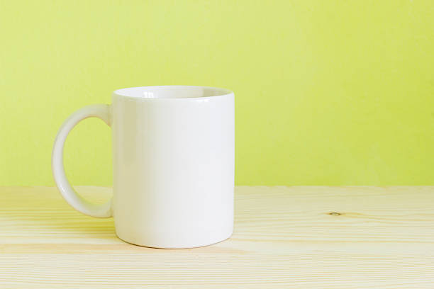 istock white cup on wooden table, green wall background 495773772
