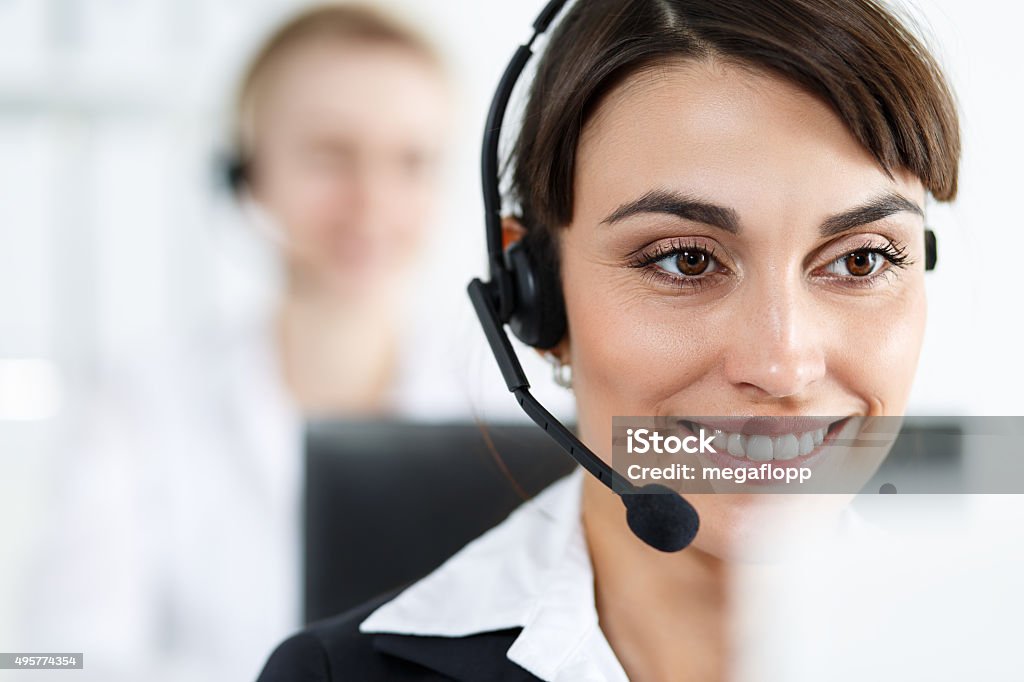 Female call center service operator at work Female call center service operator at work. Portrait of smiling pretty female helpdesk employee with headset at workplace. Effective and efficient business information, help and support concept 2015 Stock Photo