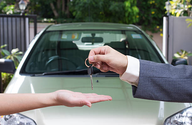 Woman buying a car and salesman handling keys stock photo