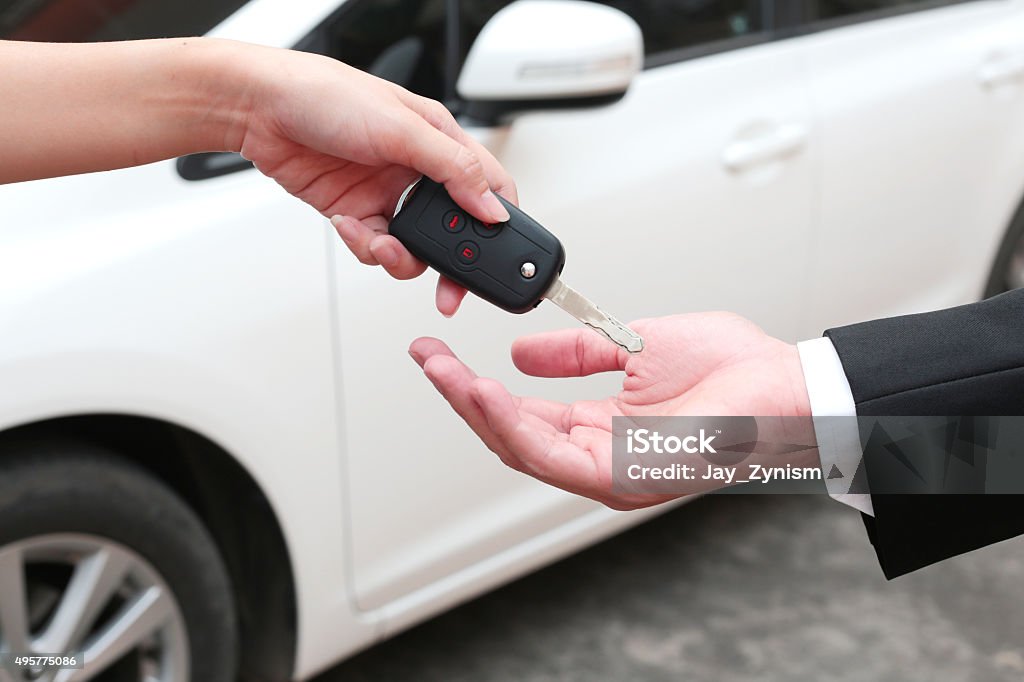 Female hand giving a key for buyer or rental car. Used Car Selling Stock Photo