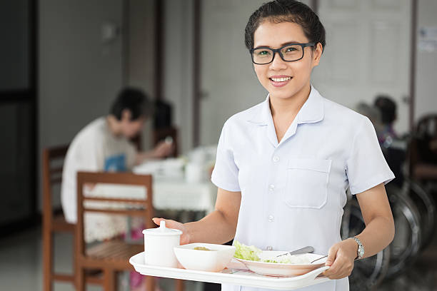 Home healthcare nurse with senior adult patient. Meal delivery caring home health care nurse delivers a hot meal to an patient at her home or nursing home facility. meals on wheels photos stock pictures, royalty-free photos & images