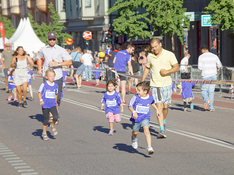 Stockholm, Sweden - August 15, 2015: Young girl, boy and father running in the section for kids of age 2-7 years in the running event Midnattsloppet, August 15, 2015 in Stockholm, Sweden