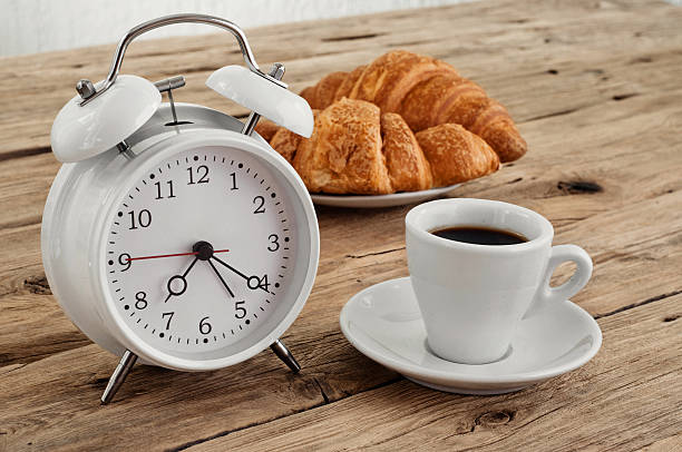 Morning coffee with alarm clock on a rustic wooden table closeup. Morning breakfast. Copy space