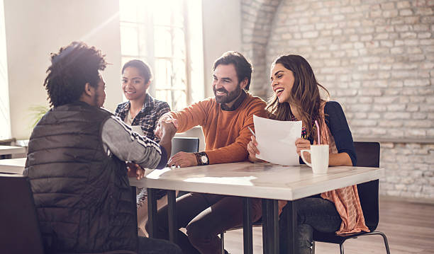 Congratulations, you've got a job! Smiling business team congratulating young man on getting a job. Men are shaking hands. casual job interview stock pictures, royalty-free photos & images