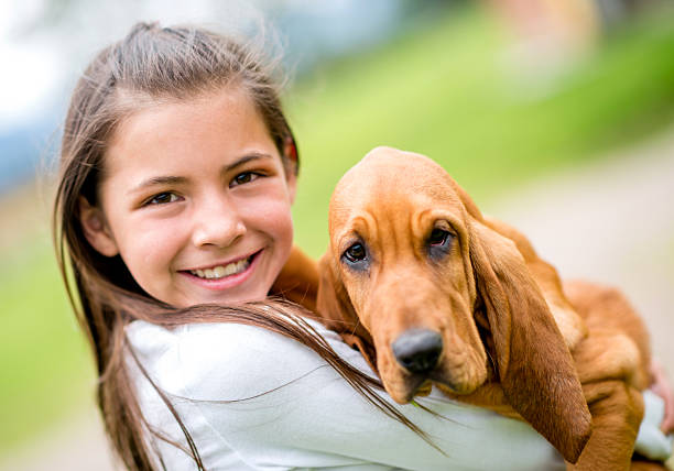 Happy girl holding a puppy and smiling outdoors