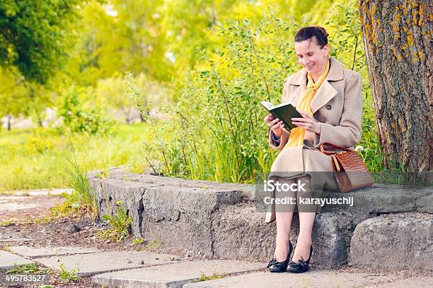 Foto de Mulher Lendo Um Livro No Parque e mais fotos de stock de Adulto - Adulto, Adulto maduro, Amarelo