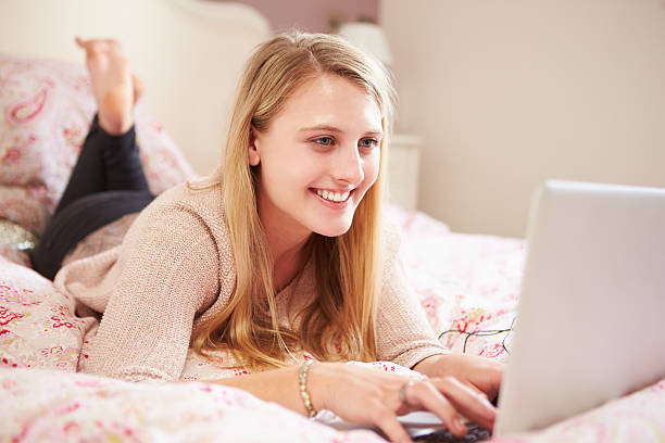 istock Teenage Girl Lying On Bed Using Laptop 495787277