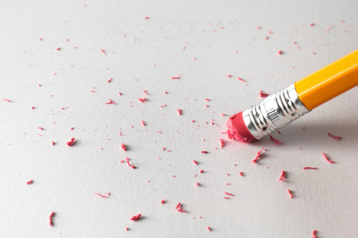 Using a pencil to erase a mistake on a sheet of white paper.