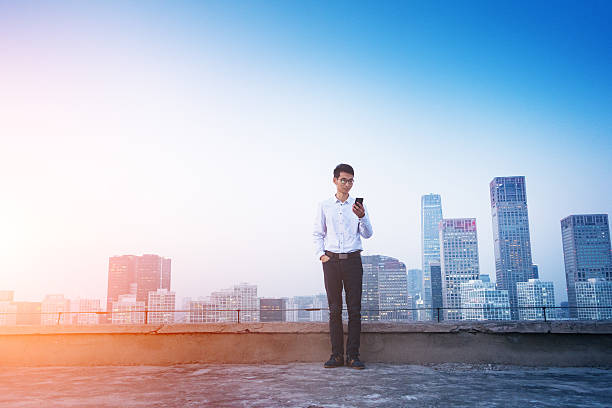 istock Businessman using smart phone standing on roof 495798988