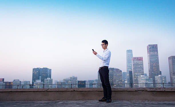 istock Businessman using smart phone standing on roof 495799102