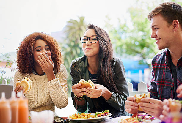 Good food and laughter go hand-in-hand Cropped shot of three friends eating burgers outdoorshttp://195.154.178.81/DATA/i_collage/pi/shoots/784741.jpg mouth full stock pictures, royalty-free photos & images