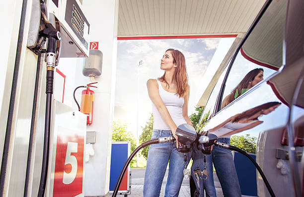 graziosa giovane donna fare rifornimento auto - fossil fuel fuel and power generation fuel pump gasoline foto e immagini stock