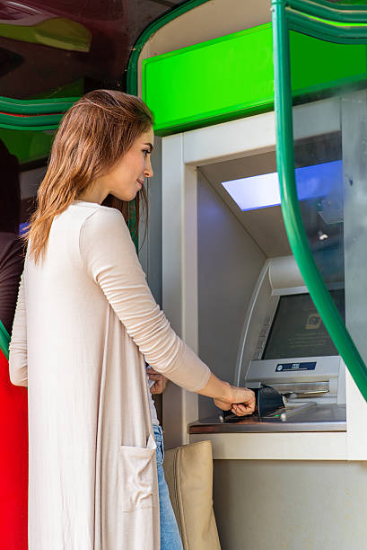 istock Young pretty woman at the ATM machine 495802432