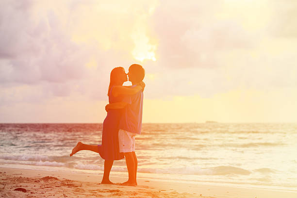 istock young romantic couple on the beach at sunset 495805588