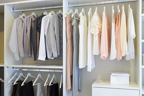 row of white dress and shirts hanging in white wardrobe stock photo