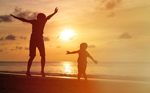 istock father and son jumping at sunset beach 495806934