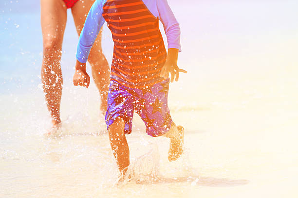 istock little boy with mother playing splashing water on beach 495807256