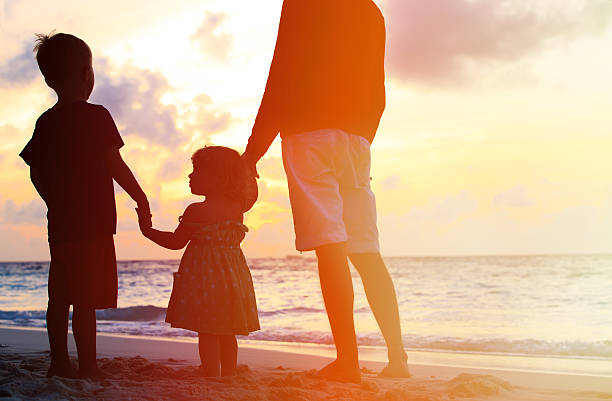 istock father and two kids walking on beach at sunset 495808288