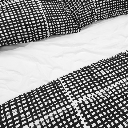 Bed with black and white checked bed linen and pillows.