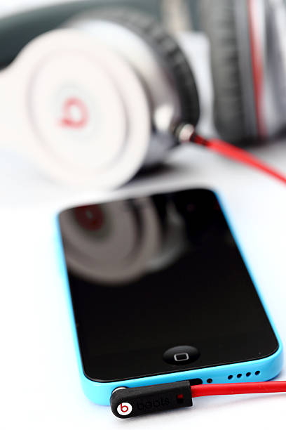 Apple iPhone 5C with Beats Headphones by Dr. Dre Placentia, CA, USA - June 2, 2014: Beats by Dr. Dre connected to an Apple iPhone 5C on white background, close up.   dre stock pictures, royalty-free photos & images