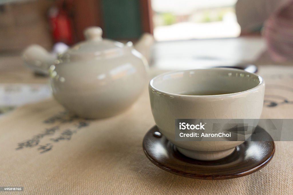 ceramic tea cup Ceramic south korean tea cup filled with tea. Teapot in the background defocused Asia Stock Photo